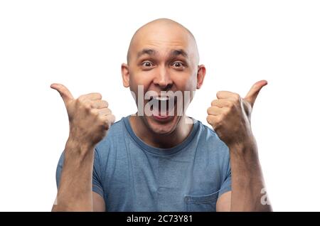 Photo du jeune homme bald heureux dans le tee-shirt montrant les pouces Banque D'Images