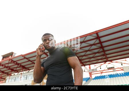 beau sportif afro sérieux à la peau sombre, parlant au téléphone. gros plan. vue à angle bas. technologie, concept de gadget. espace de copie Banque D'Images