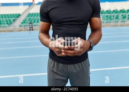 un homme musclé et bien construit qui tape un message, fait un appel téléphonique, photo rognée en gros plan. Banque D'Images