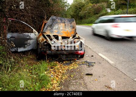 S'est écrasé, détruit et brûlé voiture abandonnée à côté gauche le côté d'un chemin de campagne. Banque D'Images