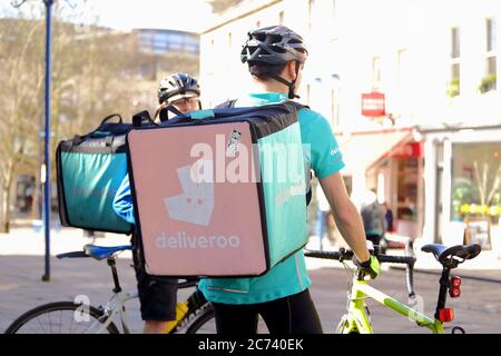 Deux Deliveroo riders livrent des plats à emporter dans une boîte à vélo dans la rue, Bath, Angleterre, Royaume-Uni.la photo a été prise le 13 mars 2017. Banque D'Images