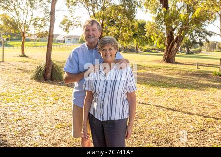 Portrait d'un couple de personnes âgées de race blanche dans les années 70, qui s'embrasse en montrant l'amour et l'affection dans le parc. Vieillir ensemble, amour, style de vie de retraite et de retour Banque D'Images