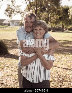 Portrait d'un couple de personnes âgées de race blanche dans les années 70, qui s'embrasse en montrant l'amour et l'affection dans le parc. Vieillir ensemble, amour, style de vie de retraite et de retour Banque D'Images
