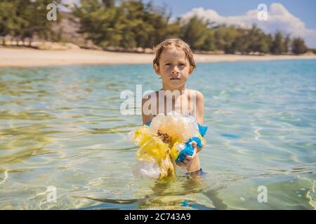 Garçon collecte des paquets de la belle mer turquoise. Pollution de plage paradisiaque. Problème de déversés déchets de déchets de déchets de déchets sur le sable de plage causé par Banque D'Images