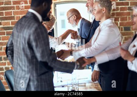 Groupe d'hommes d'affaires à la table dans le bureau qui se secouent. Banque D'Images