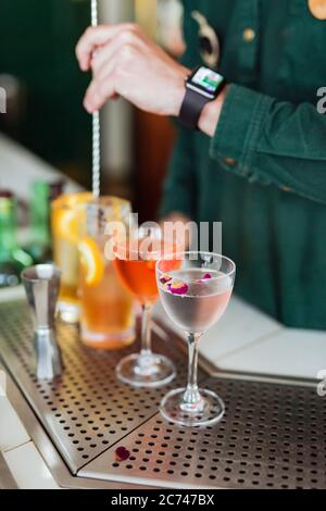 Plusieurs cocktails magnifiques au bar, barman en remuant l'un d'eux sur le fond Banque D'Images