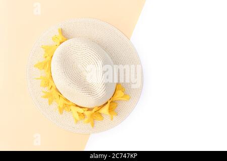 Chapeau de paille avec fleurs de nénuphars jaunes sur fond blanc et isolé. Modèle rétro élégant. Fond jaune. Conc. Mode été Banque D'Images