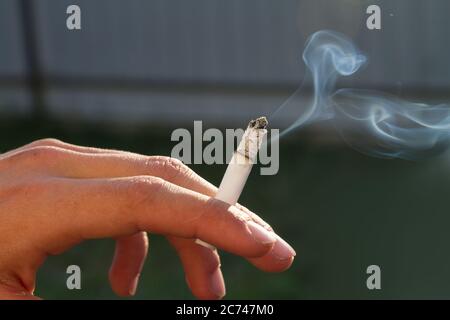 Main d'un adolescent tenant une cigarette allumée. Banque D'Images