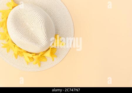 Chapeau de paille avec fleurs de nénuphars jaunes sur fond pastel. Modèle rétro élégant. Fond jaune. Concept de mode d'été. Copier l'espace. FL Banque D'Images