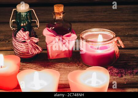 Belles bougies roses romantiques avec des bouteilles d'arôme sur fond de bois. Banque D'Images