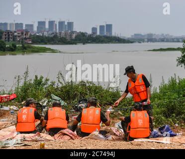 (200714) -- POYANG, 14 juillet 2020 (Xinhua) -- des policiers armés font une pause dans le remblai du comté de Poyang, dans la province de Jiangxi, en Chine orientale, le 13 juillet 2020. Avec l'eau montante de la rivière Changjiang sur le point de s'écouler sur le remblai près du comté de Poyang, les troupes de police armée sont venues rejoindre les opérations de contrôle des crues qui ont construit une barrière de 1,500 mètres de long et de 1.5 mètres de haut sur le remblai. Liu Yifei, Ma Paishan, Yang Zeyu, Yuan long et Zhu Renpeng, tous nés après 2000, se sont joints pour la première fois à une telle bataille de contrôle des inondations depuis qu'ils ont rejoint la troupe. Presque tous les jours Banque D'Images