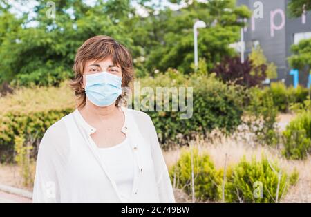 Femme avec un masque. Une femme plus âgée marchant dans la rue avec un masque de protection. Nouvelle normale. La vie humaine à distance sociale. Sécurité et pandémie concept. Banque D'Images