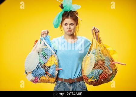 La fille dans le T-shirt bleu tient des sacs en plastique et des articles de bénévolat Banque D'Images