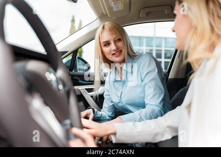 Femme élégante sur un essai de conduite avec un instructeur. Une femme s'est mise à conduire une voiture Banque D'Images