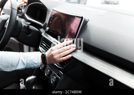 Une femme tord les commandes de l'autoradio. Écoute de la radio dans la voiture Banque D'Images