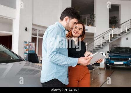 Couple regardant le catalogue de concession de voiture Banque D'Images