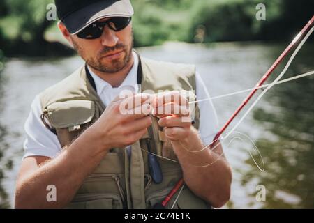 Jeunes pêcheurs pêchant sur le lac ou la rivière. Image du processus utilisant un peu de leurre pour la ligne de pêche avant de la mettre dans l'eau pour attraper de délicieux poissons Banque D'Images