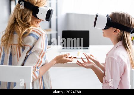 Femme souriante utilisant des micro-casques vr avec sa fille à la maison Banque D'Images