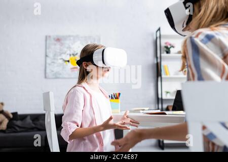 Mise au point sélective de l'enfant utilisant un casque vr près de la mère et de la papeterie sur la table Banque D'Images