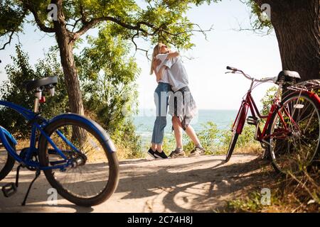 Un couple magnifique s'embrassant en se tenant dans le parc avec une vue incroyable sur la mer en arrière-plan. Jeune couple mignon passer du temps avec le rouge Banque D'Images