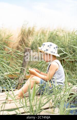 un petit garçon dans un chapeau est la pêche dans les roseaux Banque D'Images