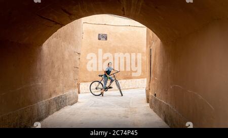 Yazd, Iran - Mai 2019: Enfant sur un vélo dans la rue étroite de la vieille ville Yazd, Iran. Banque D'Images