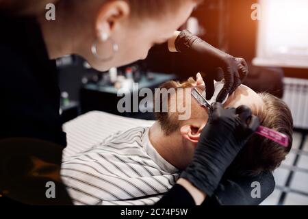 Barbier se raser un homme dans un salon de coiffure, gros plan Banque D'Images