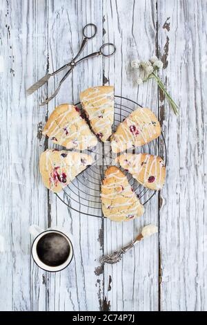 Scones anglais traditionnel frais de canneberge ou de thé de cerise sur fond rustique avec une tasse de café chaud. Plan d'étapage plat. Banque D'Images