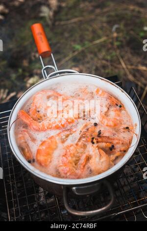 Crevettes rouges et langoustines dans l'eau bouillante - fruits de mer surgelés et bouillis Banque D'Images