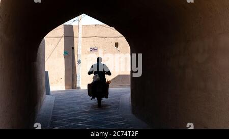 Yazd, Iran - Mai 2019: Homme sur une moto dans la rue étroite de la vieille ville Yazd, Iran. Banque D'Images