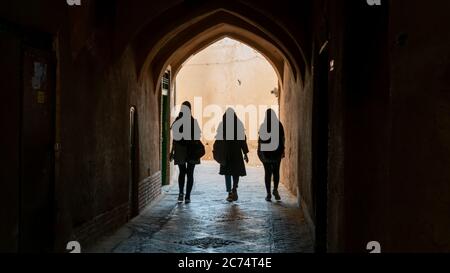 Yazd, Iran - Mai 2019 : des femmes non identifiées marchant dans la rue étroite de la vieille ville de Yazd, Iran. Banque D'Images