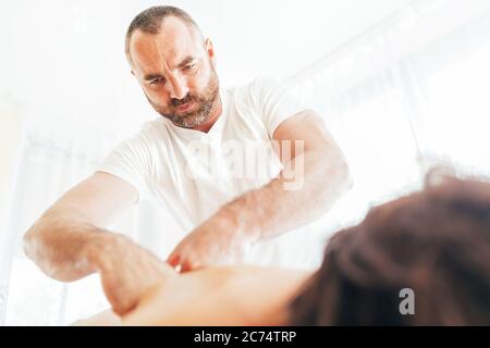 Homme de masseur barbu effectuant des manipulations de massage sur la zone de Scapula pendant le massage de corps de jeune femme. Image de concept de soins de santé. Banque D'Images