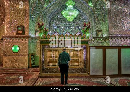 Shiraz, Iran - Mai 2019 : homme non identifié priant à l'intérieur du sanctuaire et mausolée de Shah e Cheragh, la mosquée miroir Banque D'Images