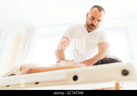 Homme de masseuse faisant des manipulations de massage sur le dos du client et de communiquer avec pacient Banque D'Images