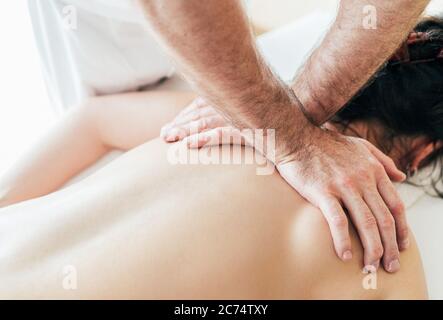 Homme du masseur mains effectuant des manipulations de massage sur la zone de Scapula pendant le massage du corps de la jeune femme. Banque D'Images