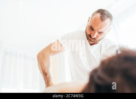 Homme de masseuse barbu effectuant des manipulations de massage sur la partie basse du dos pendant le massage. Image de concept de soins de santé Banque D'Images