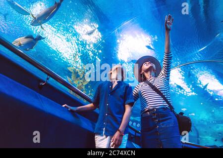 Fils avec sa mère regardant les habitants sous-marins de la mer dans un immense tunnel d'aquarium, montrant un intéressant pour l'autre Banque D'Images