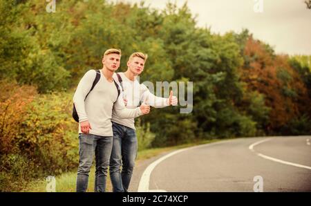 Voyageurs en route. Des amis qui voyagent avec des hitchhikers. Geste de randonnée. Commencez une grande aventure dans votre vie avec la randonnée pédestre. Compagnie amis voyageurs qui déchire à la route nature fond. Banque D'Images