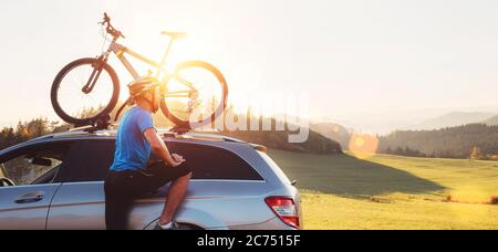 Homme prendre son vélo de toit de voiture. Concept VTT Banque D'Images