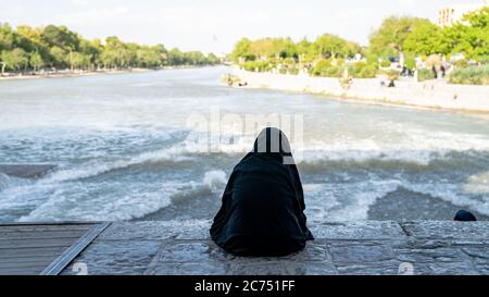 Ispahan, Iran - Mai 2019 : femme iranienne assise près du fleuve Zayandeh sur le pont de Khaju Banque D'Images