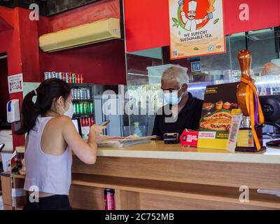 SINGAPOUR – 10 2020 JUILLET – UN client du restaurant indien Springleaf Prata place à Singapour porte un masque de protection et paie par téléphone mobile c Banque D'Images
