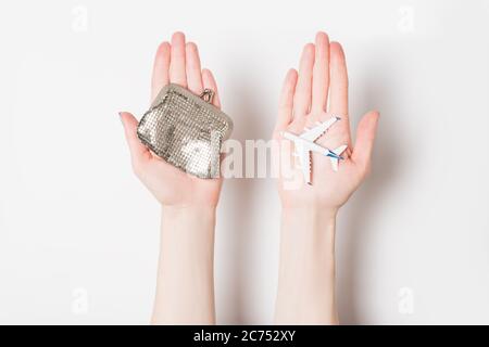 Avion passager et portefeuille sur les paumes femelles sur un fond clair. Vols bon marché. Banque D'Images