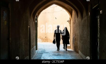 Yazd, Iran - Mai 2019: Couple non identifié marchant dans la rue étroite de la vieille ville Yazd, Iran Banque D'Images