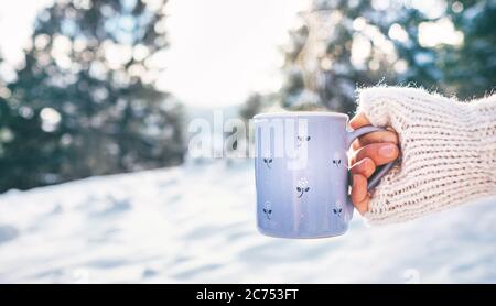 Femme prendre en main une tasse de boisson chaude. Hiver forêt de glade, scène de soleil lumineux Banque D'Images