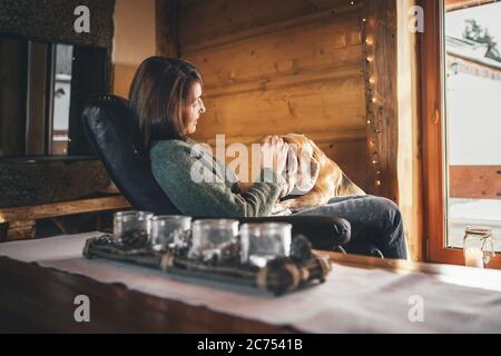 Scène tendre avec la femme et son chien de beagle dans une chaise confortable en face de la grande fenêtre dans la maison de campagne confortable. Vacances à la campagne avec animaux concept imag Banque D'Images