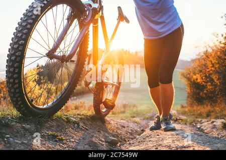 Cycliste poussant un VTT en haut de la colline image de gros plan. Déplacement actif à vélo Banque D'Images