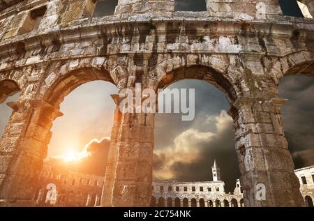 Vue sur le clocher de l'église à travers les arches de l'amphithéâtre avec fond violet ciel de lever de soleil Banque D'Images