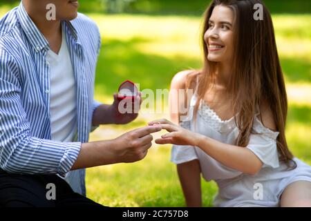 Proposition d'été. Un homme affectueux qui met l'anneau d'engagement sur le doigt de la femme dans le parc Banque D'Images