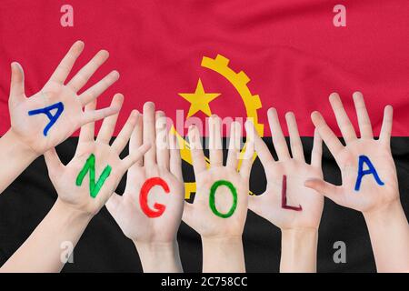 Inscription Angola sur les mains des enfants sur fond de drapeau agitant de l'Angola Banque D'Images