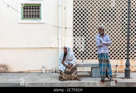 Pondichéry. Inde - février 2020 : un homme et une femme indiens âgés qui attendent sur un trottoir dans la vieille ville de Pondichéry. Banque D'Images